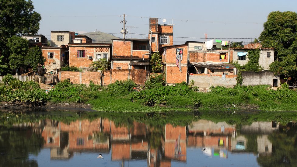 Casas precárias, sem pintura, na beira de canal poluído no Rio de Janeiro
