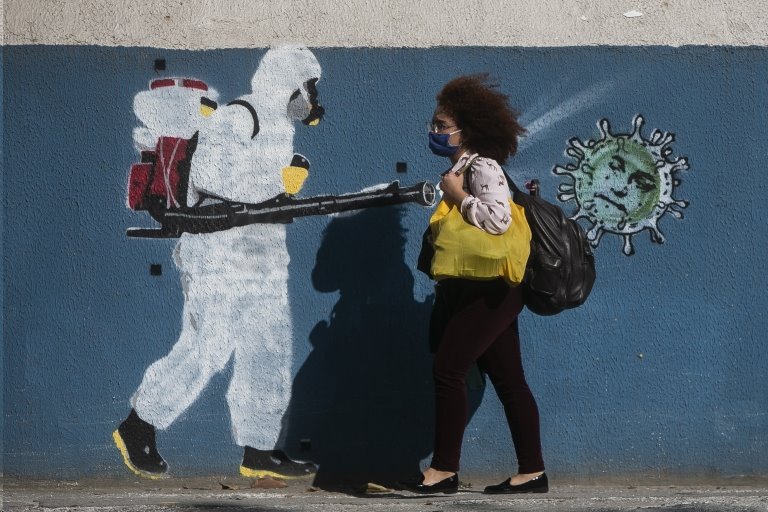 Mulher caminha diante de grafiti no Rio