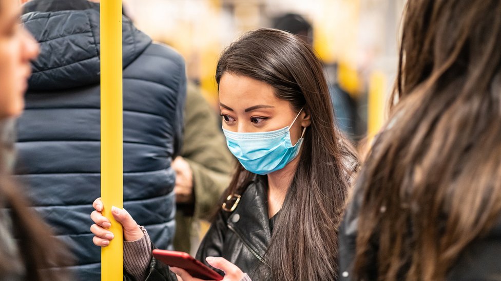 Mulher no metrô com máscara