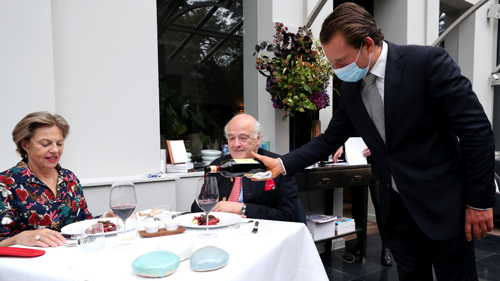 Garçom serve clientes em restaurante na Bélgica