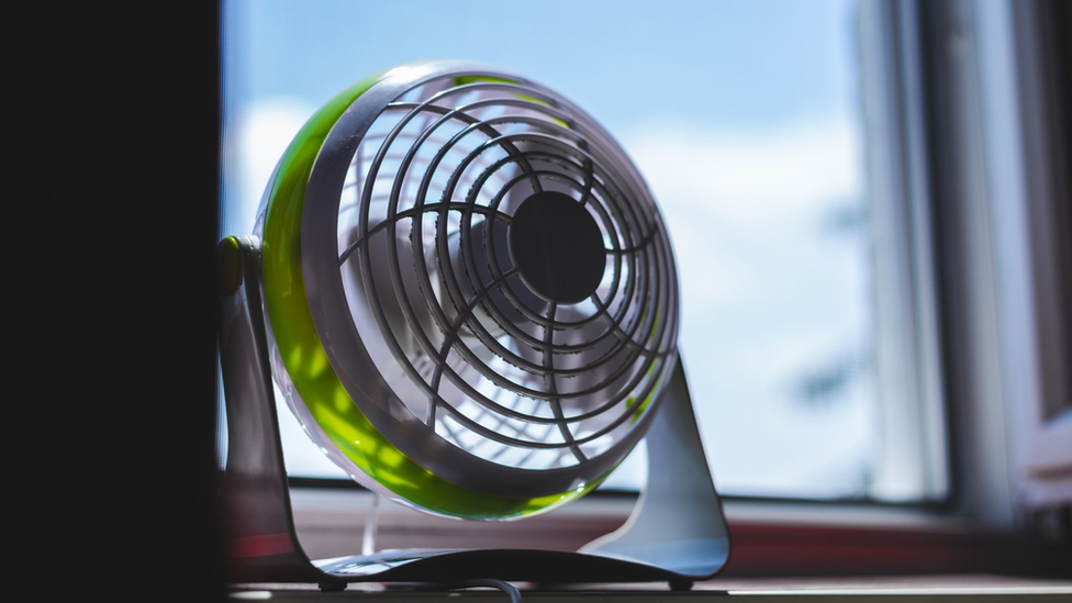 Pequeno ventilado apoiado em mesa perto de janela