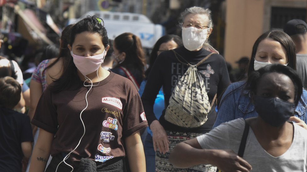 Pessoas na rua com máscara