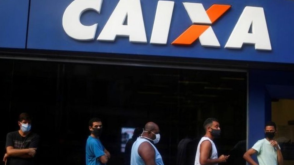 Fachada da Caixa com fila de pessoas com máscara na porta