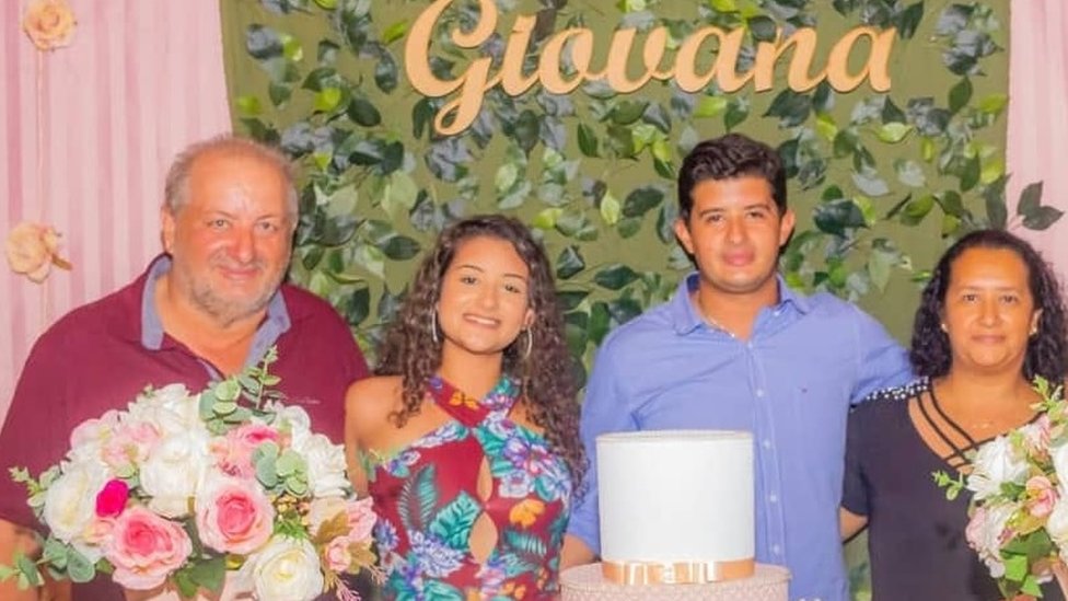 Pais de Giovana e a jovem em foto antiga, tirada em frente a uma mesa de festa