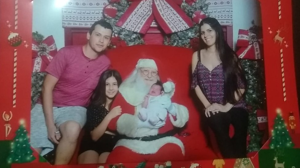 Família de Gabriel e Ana Cláudia posa em cenário natalino junto com Papai Noel, que segura a recém-nascida em seus braços