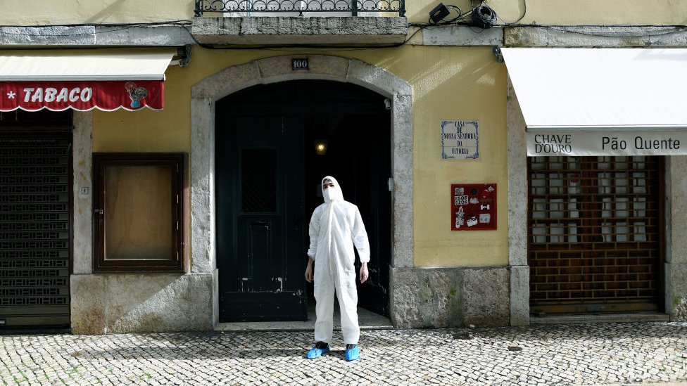 Homem com traje de proteção em rua de Lisboa