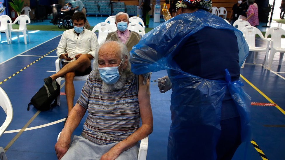 Pessoas recebendo a vacina em ginásio no Chile