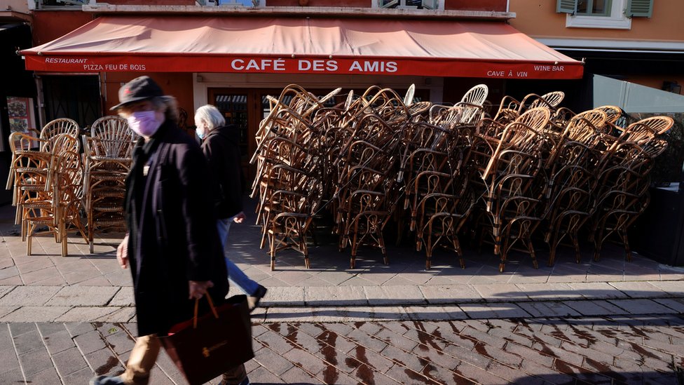 Pessoas caminhando em frente a bar fechado por confinamento na França