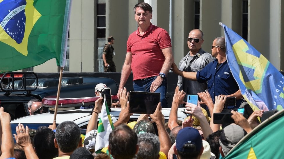 O presidente Jair Bolsonaro se prepara para falar depois de se juntar a seus apoiadores que participavam de uma carreata em protesto contra medidas de quarentena e distanciamento social para combater o novo surto de coronavírus em Brasília em 19 de abril de 2020. (Foto EVARISTO SA / AFP)