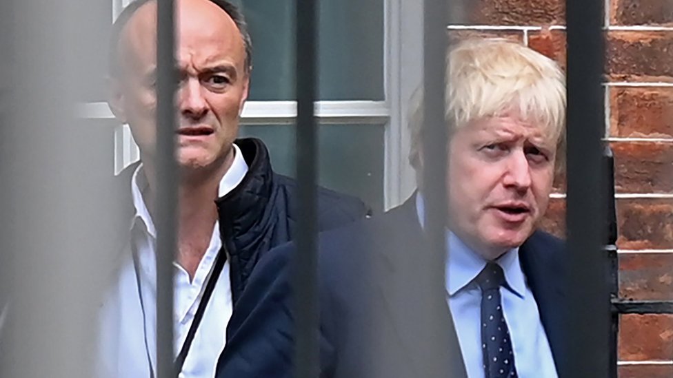 Dominic Cummings e Boris Johnson atrás de grade