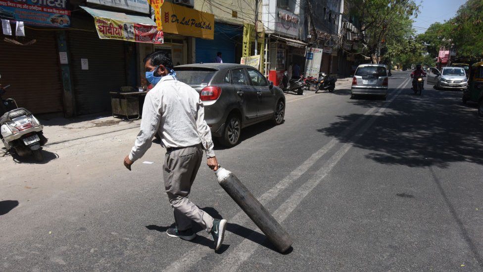 Homem carrega um cilindro vazio para reabastecê-lo fora do centro de enchimento de oxigênio na Dilshad Garden Area em 25 de abril de 2021 em Nova Delhi, Índia