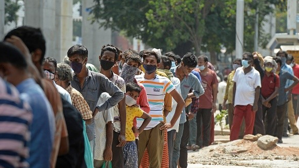 Fila de pessoas usando máscara na Índia