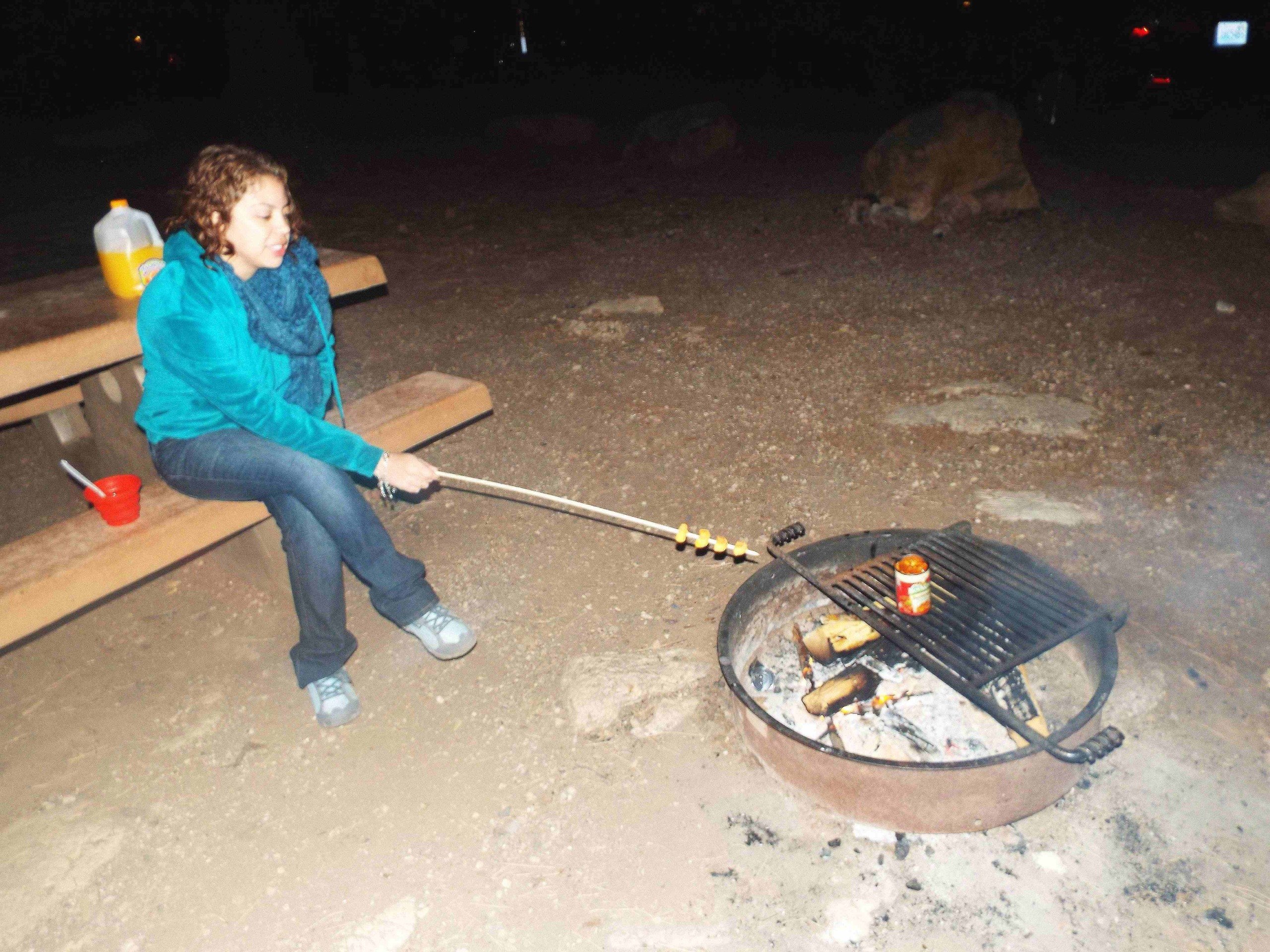 Amanda preparando a comida na fogueira do camping