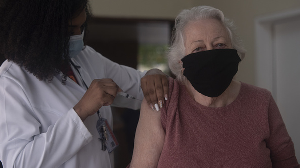 Idosa recebe vacina de profissional da saúde