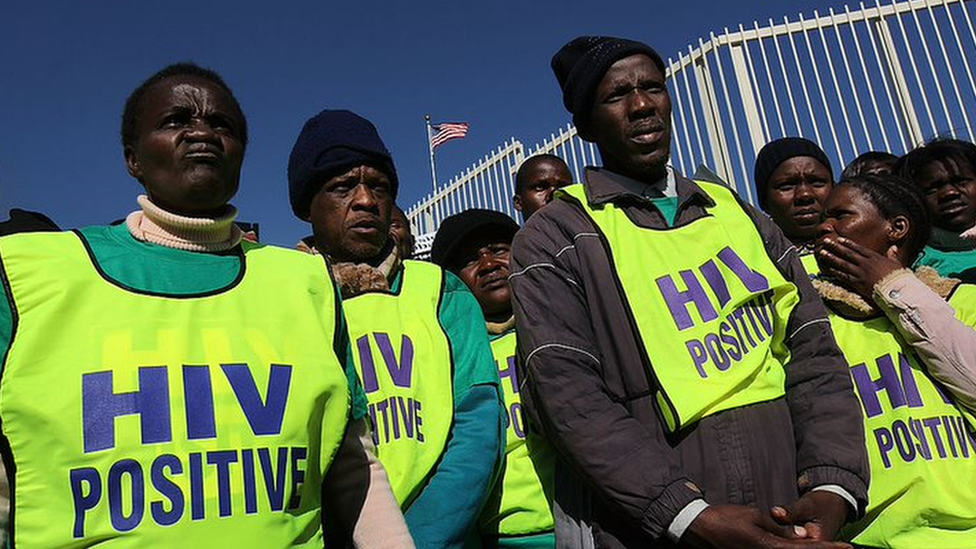 Dezenas de pessoas com colete dizendo 'Hiv positive' sob céu azul