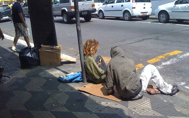 Pessoas em situação de rua sentadas no chão