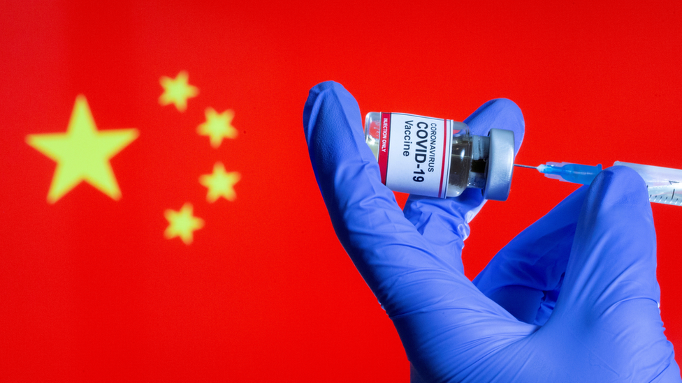 Uma vacina contra covid em frente a uma bandeira chinesa