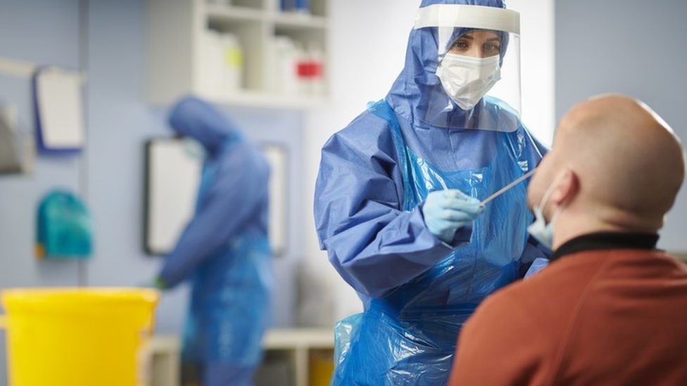 Profissional de saúde insere swab no nariz de paciente