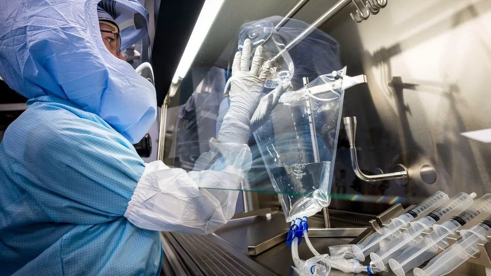 Pesquisadores paramentados mexem em equipamento em laboratório