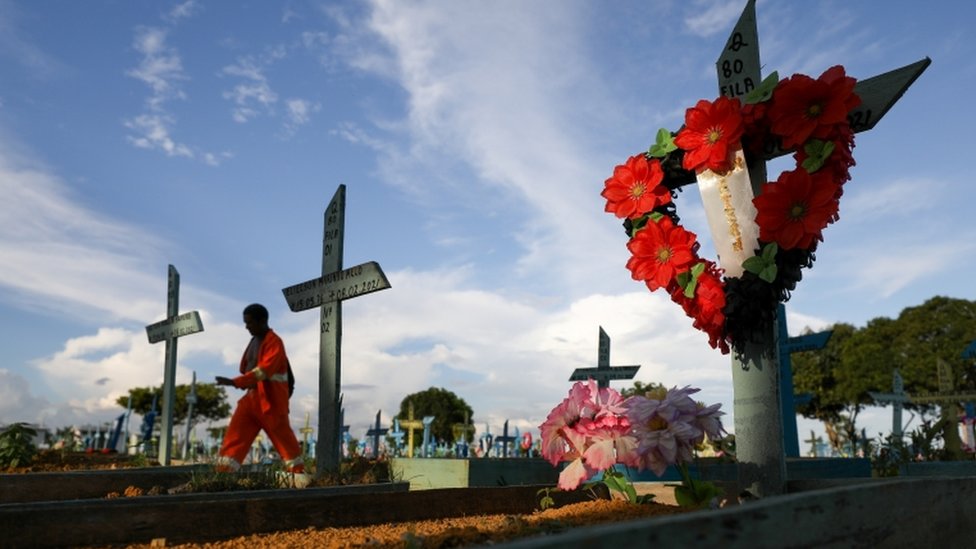 Cemitério com coroas de flores em locais onde pessoas estão enterradas