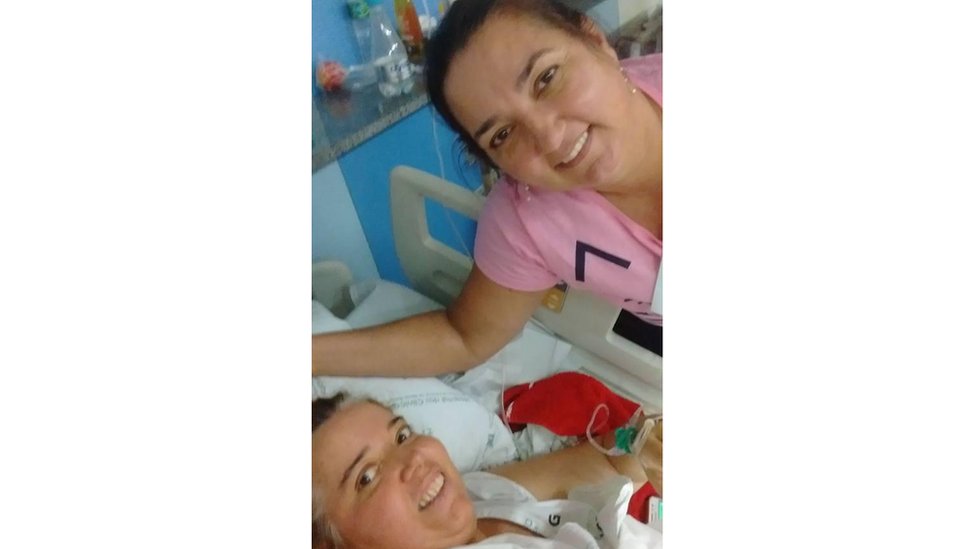 Ruth e Margareth (deitada no leito de hospital) sorriem para foto