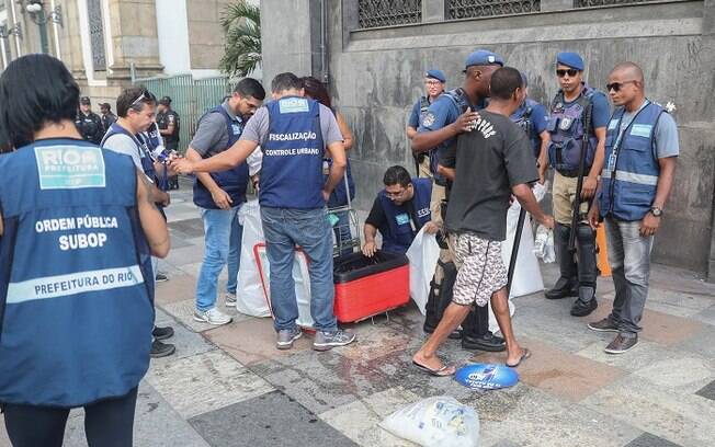 Vendedores ambulantes tendo mercadorias vistoriadas