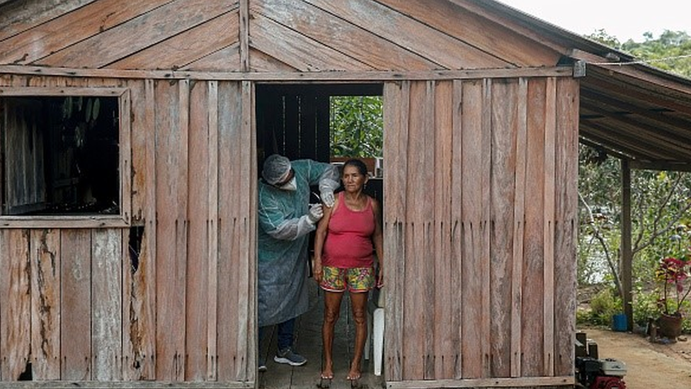 Mulher é vacinada em casa de madeira