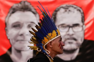 Manifestante em frente a imagem de jornalista britânico Dom Phillips e de indigenista Bruno Pereira em Brasília