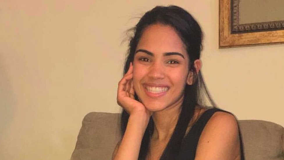 Crisleidy sentada em um sofá