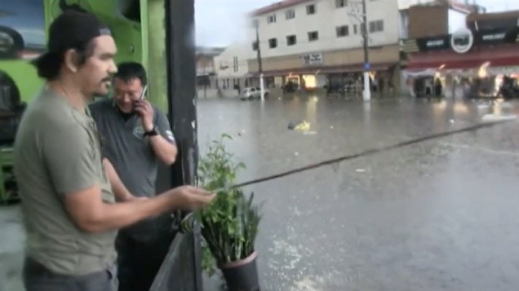 Homem pesca em enchente durante temporal em São Paulo