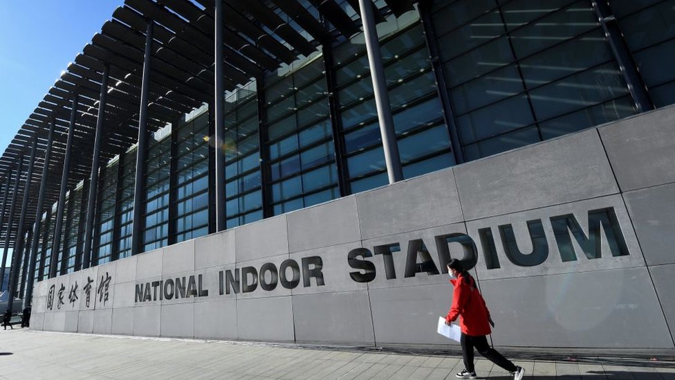Mulher passa pelo National Indoor Stadium antes de uma partida de hóquei no gelo, parte de um evento-teste dos Jogos Olímpicos de Inverno de Pequim em 2022, em Pequim, em 10 de novembro de 2021
