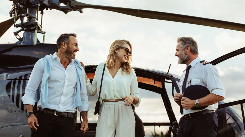 Casal e piloto em frente a um helicóptero