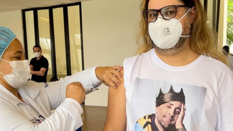 Marcos Majella toma vacina para Covid usando camiseta com rosto de Paulo Gustavo