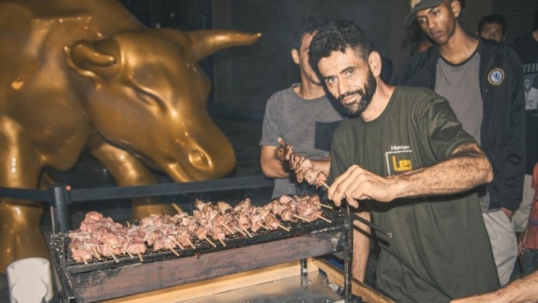 Após protesto, ONG faz churrasco com população de rua em frente ao Touro de Ouro
