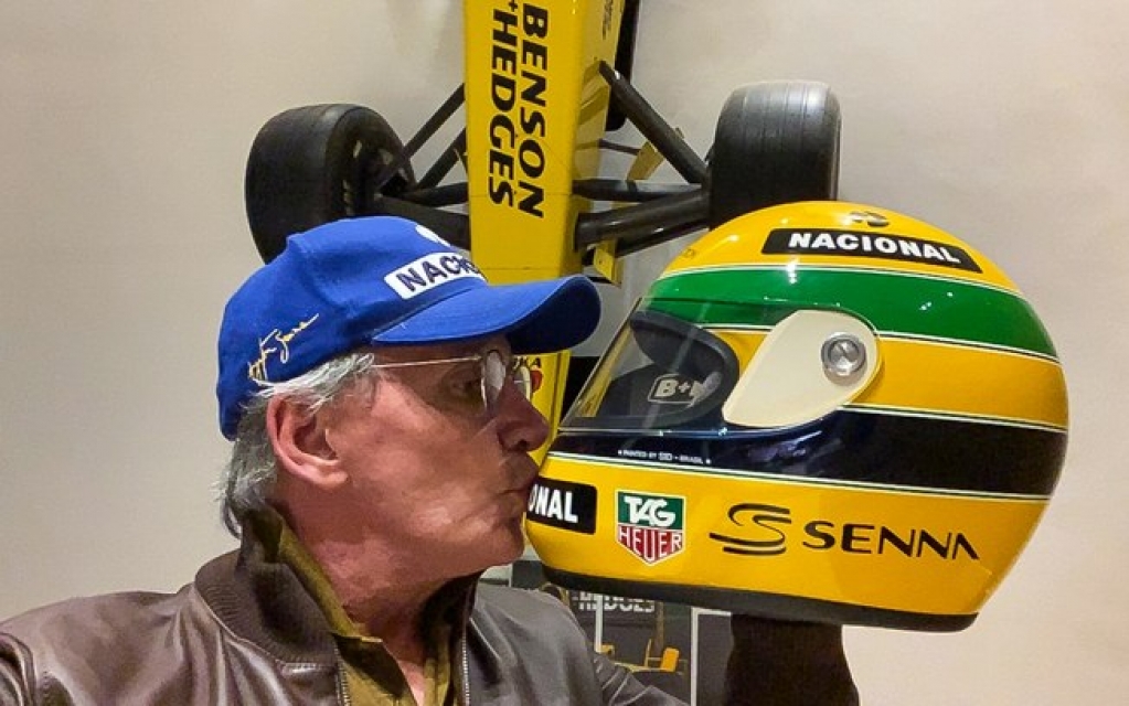 Otávio Mesquita posa beijando capacete de Ayrton Senna por videoconferência