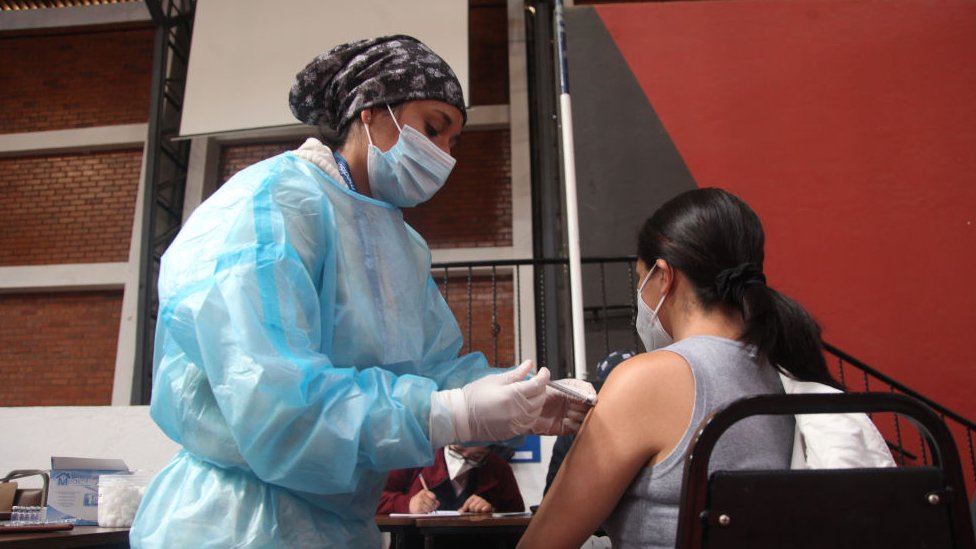 Profissional de saúde vacina uma mulher no Equador
