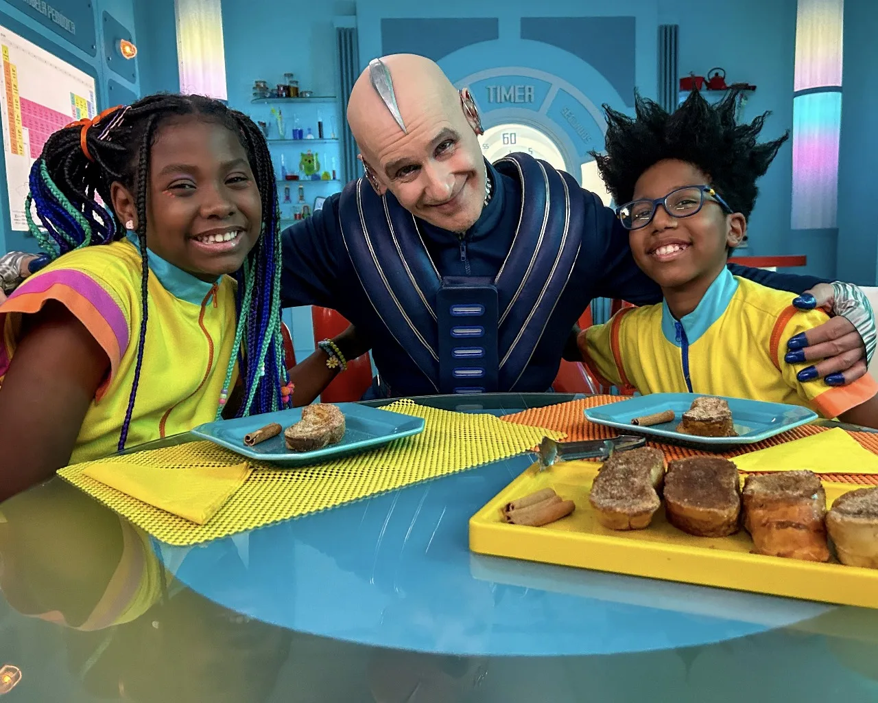 Cientistas-chefs Maya (Valentina Leão) e Tom (Ygor Marçal) com o robô Chicô (Ruben Gabira) 